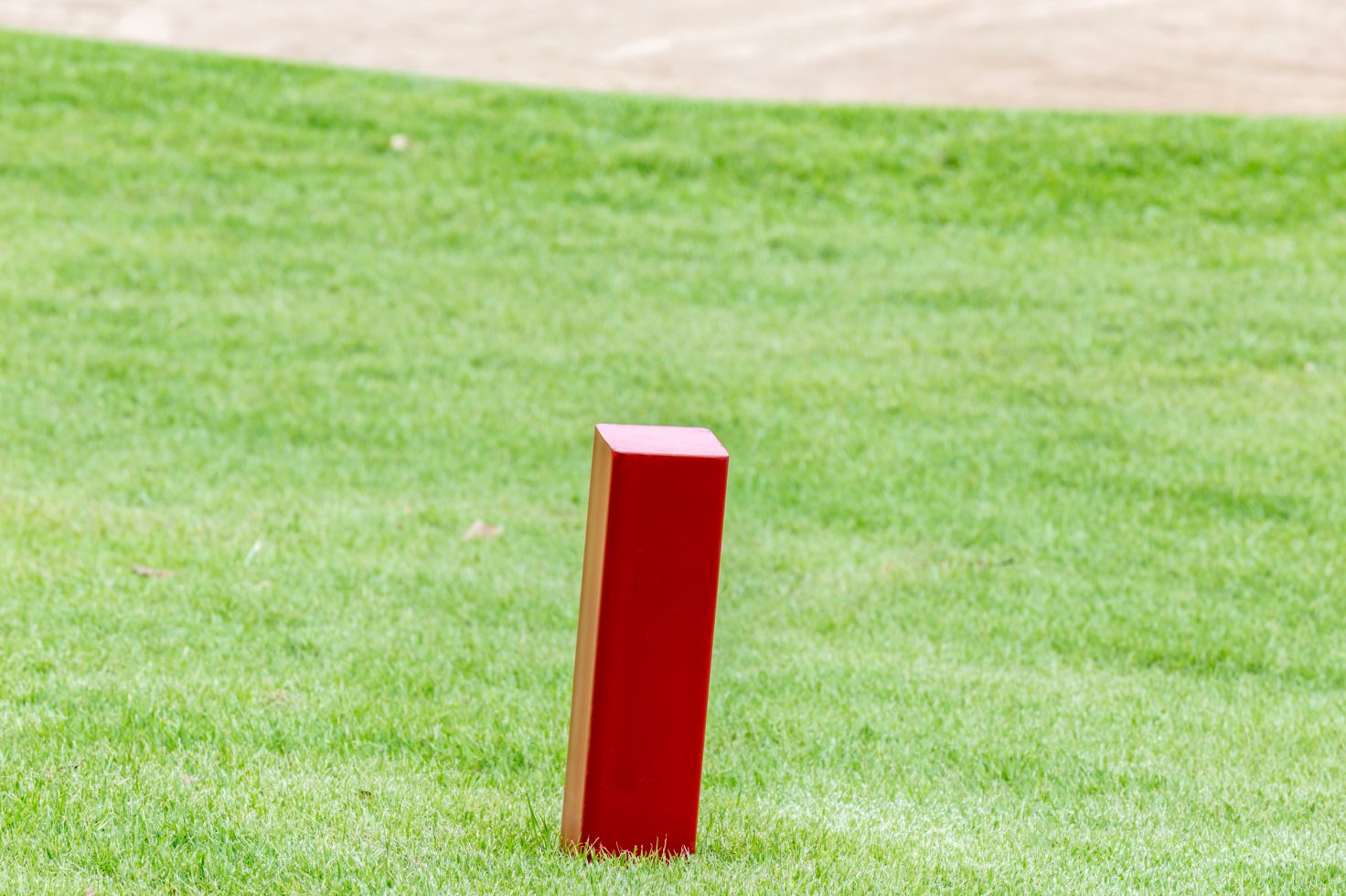 The red distance marker pole to inform range of golfing with blurred green golf course. Getty Images/iStockphoto