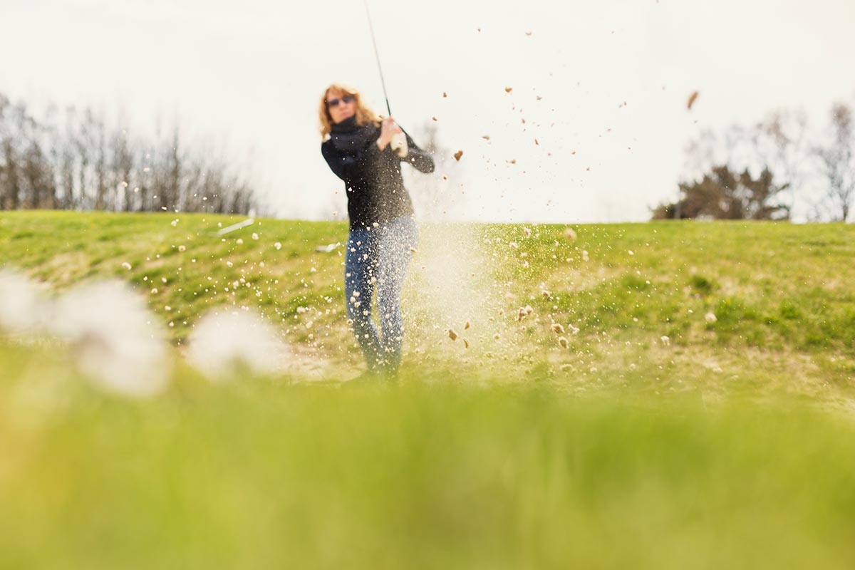 Close-up of field with woman playing golf in background at golf course Lisa Lindqvist Liljedahl